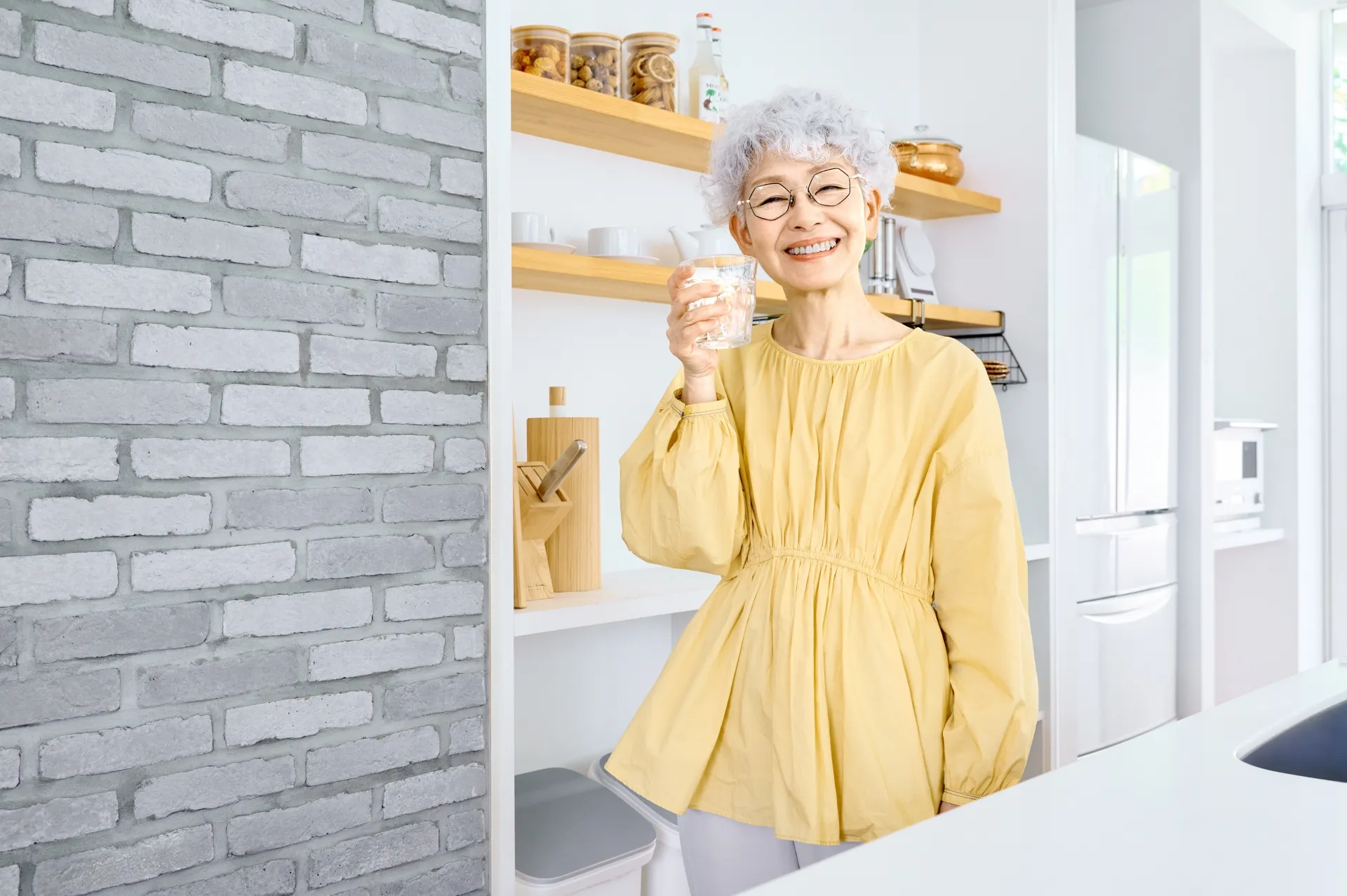 白湯を片手に笑顔で朝活のアイディアを話す高齢女性のイメージ画像